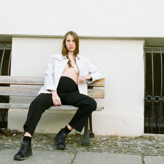 model wearing the maternity black, comfortable pants with black shoes, white jacket. a comfortable piece from the maternity box. cruba