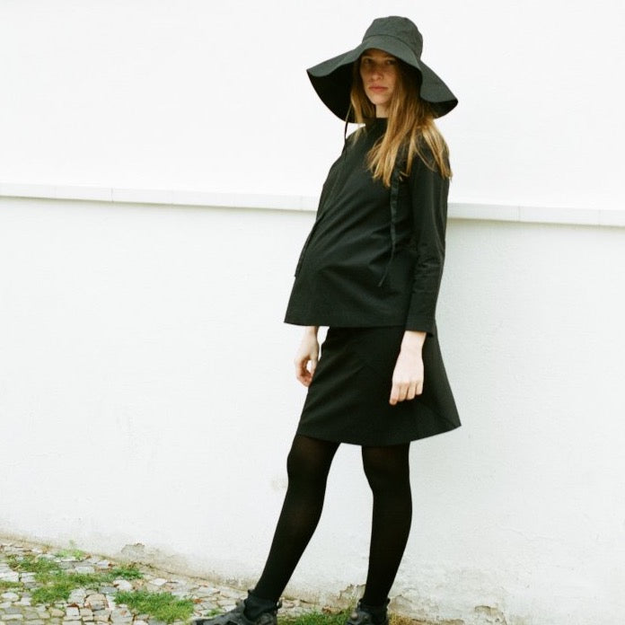 all black maternity outfit with black sun hat, pregnancy skirt and maternity long sleeved blouse. cruba