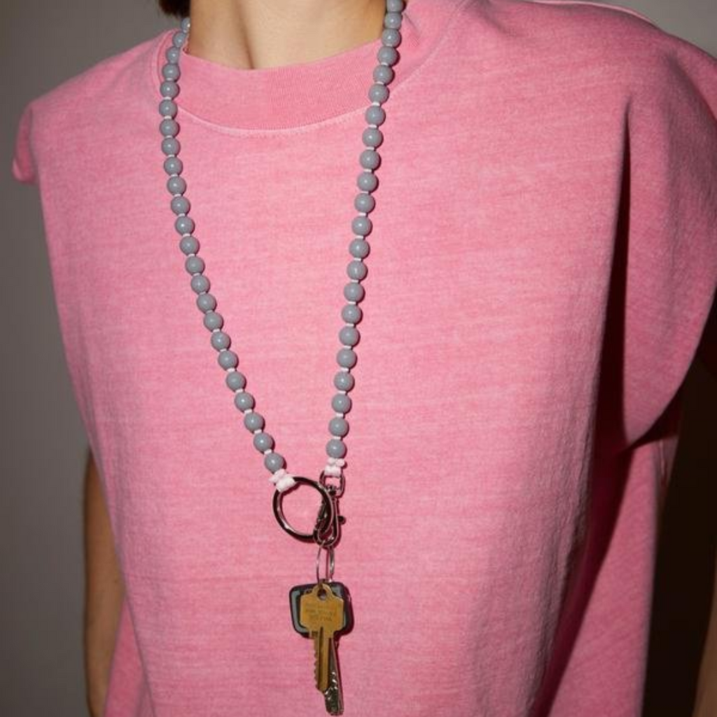 LONG INA SEIFART keychain. worn around the neck as a necklace in grey and pink. wooden beads with coloured plating and silver hardware cruba