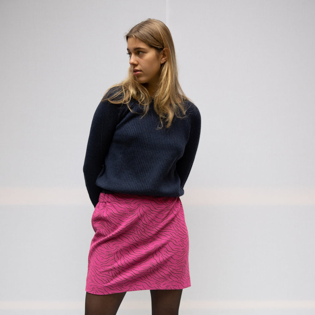 The dark blue merino wool sweater is long sleeved and can be layered with a blouse of t-shirt. The model is wearing a tiger print skirt from cruba