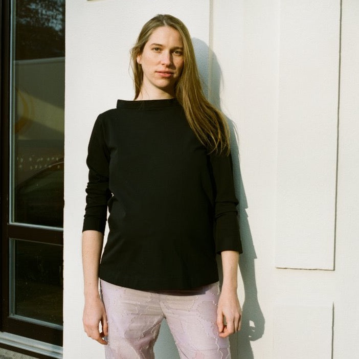 Model wearing black blouse or shirt made out of cotton with long sleeves and pink, patterned maternity pants. Unique, classic, chic cut for occasions and everyday wear. cruba